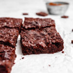 Vegan Brownies With Shiny Crackly Top On White Parchment Paper